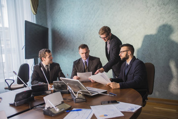 Group of four business people working on laptop at meeting, business people working together in...