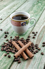 Obraz na płótnie Canvas Cinnamon sticks on coffee grains with cup coffee on green rustic table