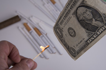fiamma e dollaro con sfondo di sigarette e sigari