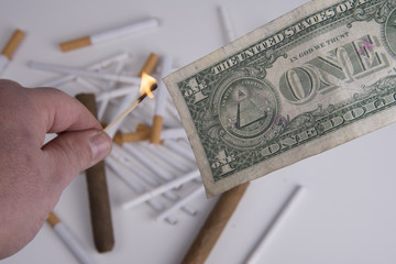 fiamma e dollaro con sfondo di sigarette e sigari