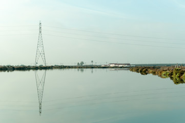Torre eléctrica de alta tensión reflejada en el agua