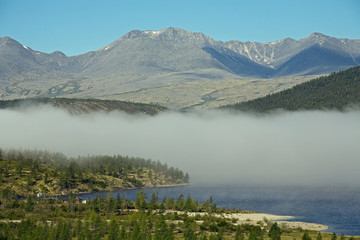 Band of mist over a mountain lake. Lake Darpir, Cherskogo Ridge, Yakutia, Russia.