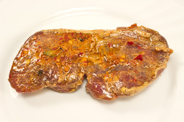 Raw steak with marinade in white plate