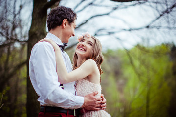 Pretty bride in pink dress hugs her man laughing