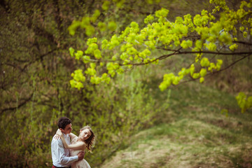 Naklejka na ściany i meble Spring branches with green leaves hang over hugging couple