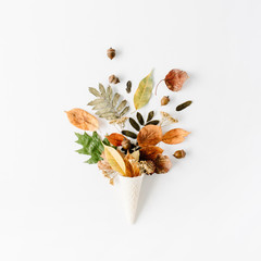 waffle cone with dried autumn leaves bouquet on white background, flat lay, top view