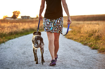 a young woman walking her dog at sunset