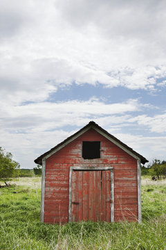 Dilapidated red shed with blue sky and cloud;Manitoba canada
