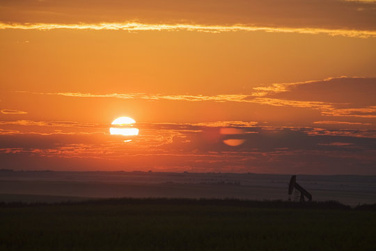 View of pumpjack in a field at sunrise 