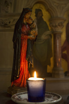 A candle burning by a small sculpture of a woman holding a child;Kelso scottish borders scotland