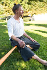 portrait of man sitting on slackline and  balancing on a rope