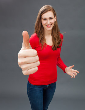 smiling young woman with thumbs up for symbol of satisfaction
