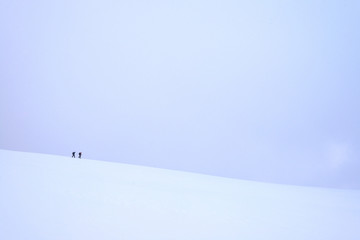 Two people walking along ridge in snow covered, winter conditions on Beinn an Dothaidh, near Bridge of Orchy; Argyll and Bute, Scotland