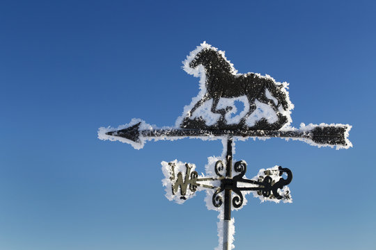 Close up of frosted weather van with blue sky; Calgary, Alberta, Canada