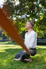 portrait of man sitting on slackline and  balancing on a rope