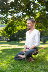 portrait of man sitting on slackline and  balancing on a rope