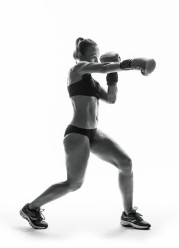 Boxer woman during boxing exercise making direct hit, isolated