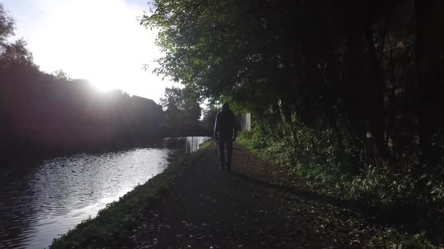 A man walking his dog on the canal.