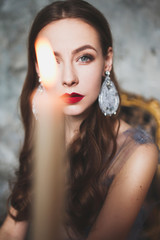 Dark princess with red lips and candles around waiting for Halloween