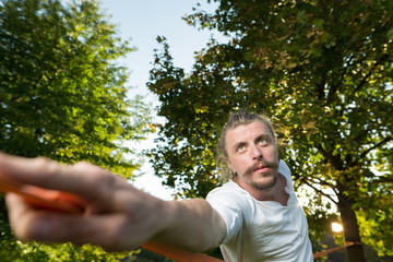 Portrait of man with long hair sitting outdoors in park while do