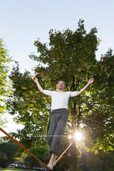 Fototapeta na wymiar Man walking barefoot on slackline in park with arms out