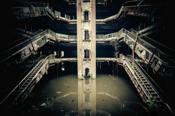 Dramatic view of damaged escalators in abandoned shopping mall sunken by rain flood waters. Apocalyptic and evil concept