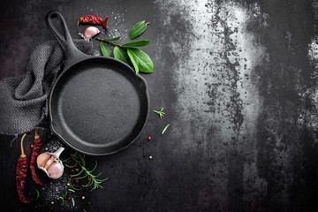 cast iron pan and spices on black metal culinary background, view from above - obrazy, fototapety, plakaty