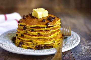Pumpkin pancakes with chocolate drops on a rustic background.