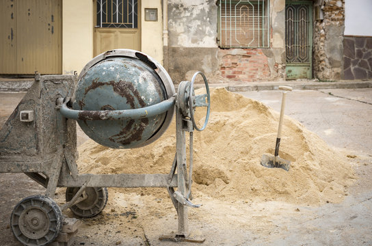 an electric cement Mixer, sand and a shovel for construction
