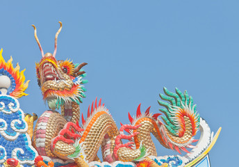 Fototapeta premium Chinese dragon statue on temple roof top under blue sky