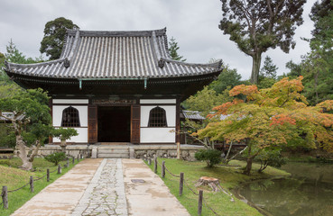 Fototapeta na wymiar Kyoto, Japan - September 19, 2016: Smaller hall of the Kodai-ji Buddhist Temple complex sits in a beautiful garden which starts to show autumn colors. Gray sky.