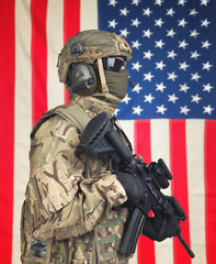 US soldier with machine gun in hands and American flag on background