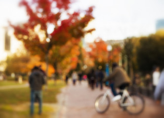 blurred background of city life. blurred red maple and the people in the park