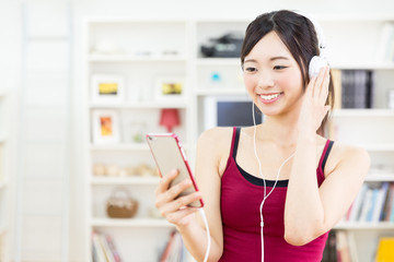 sporty asian woman listening music in the living room