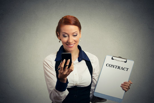 Woman using texting on mobile phone holding contract documents .