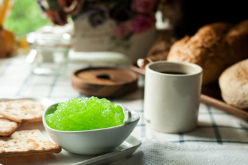 apple jam and crackers, coffee cup on the table, light from the window
