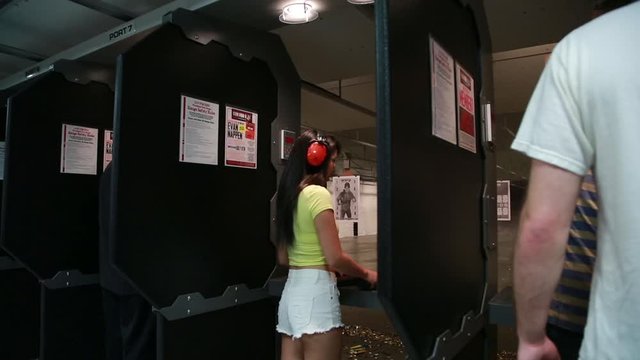 Indoor gun range, attractive young asian woman fires an AR-15 assault rifle at an indoor gun range.