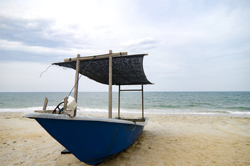 closed up fisherman boat stranded on the sandy beach and cloudy