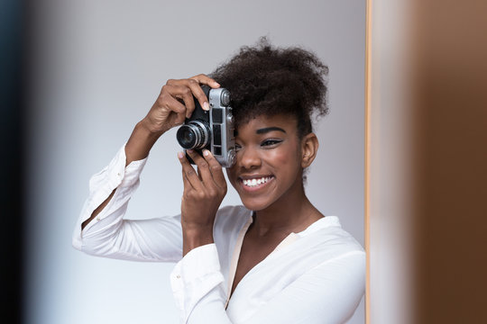 Afro american woman taking a picture with a  vintage camera