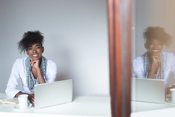 Smiling african american woman at office desktop with laptop