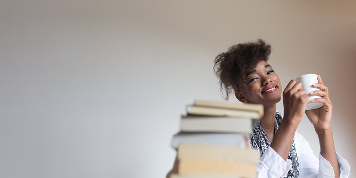 Young African American Woman Reading Book  With A Coffee Cup On