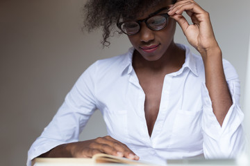 Young African American woman reading book  with a coffee cup on