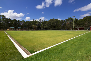 Green bowls or lawn bowls player ground which is natural grass or artificial turf surrounded with spot light, bench for players and public inside the stadium.