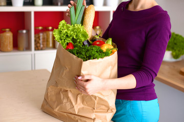 Healthy positive happy woman holding a paper shopping bag full of fruit and vegetables