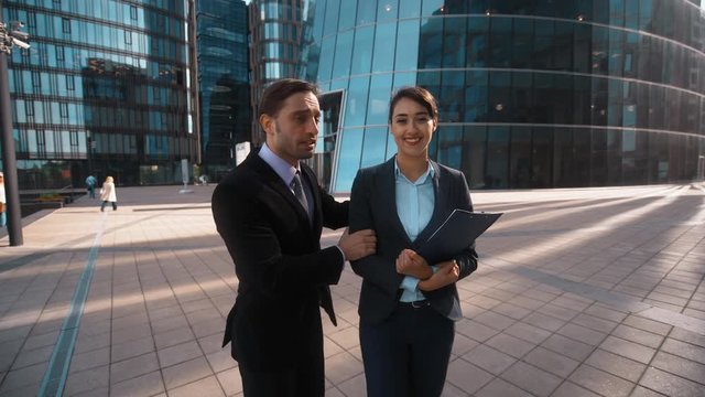 4K. POV. Young attractive Businessman in formal suit recommed his partner sexy pretty brownhair beautiful lady collegue with textpad to You. She strart to make offer. Glass building businesscentre bg