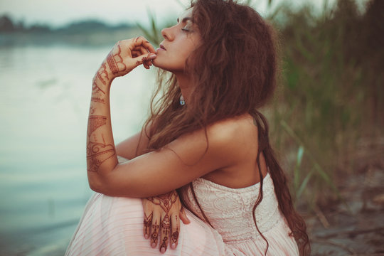 Brunette woman sits thoughtful between the high grass on the bea