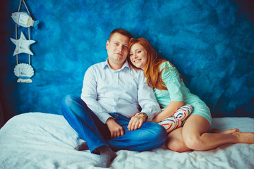 Naklejka premium Beautiful couple sits cosy on the white bed