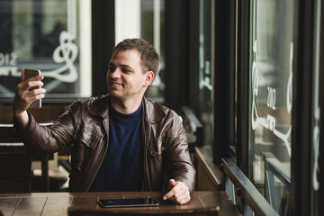 Young man taking a selfie in coffee shop