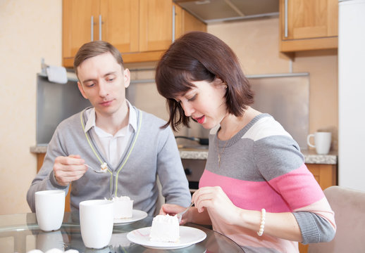  Man and woman eating in   kitchen.