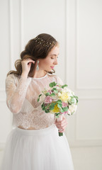 Beautiful young bride with bouquet on white.